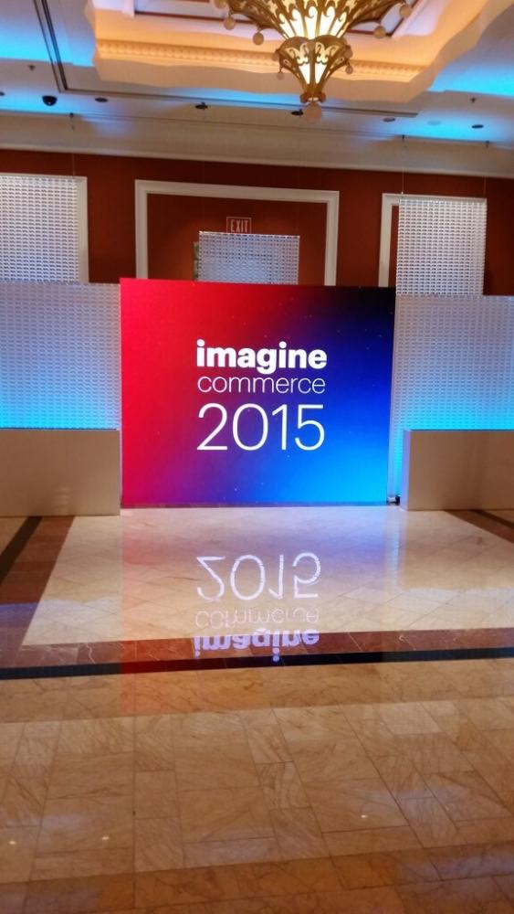 Hallway with large projector screen with the word Imagine Commerce 2015 being reflected on the shiny floor tile